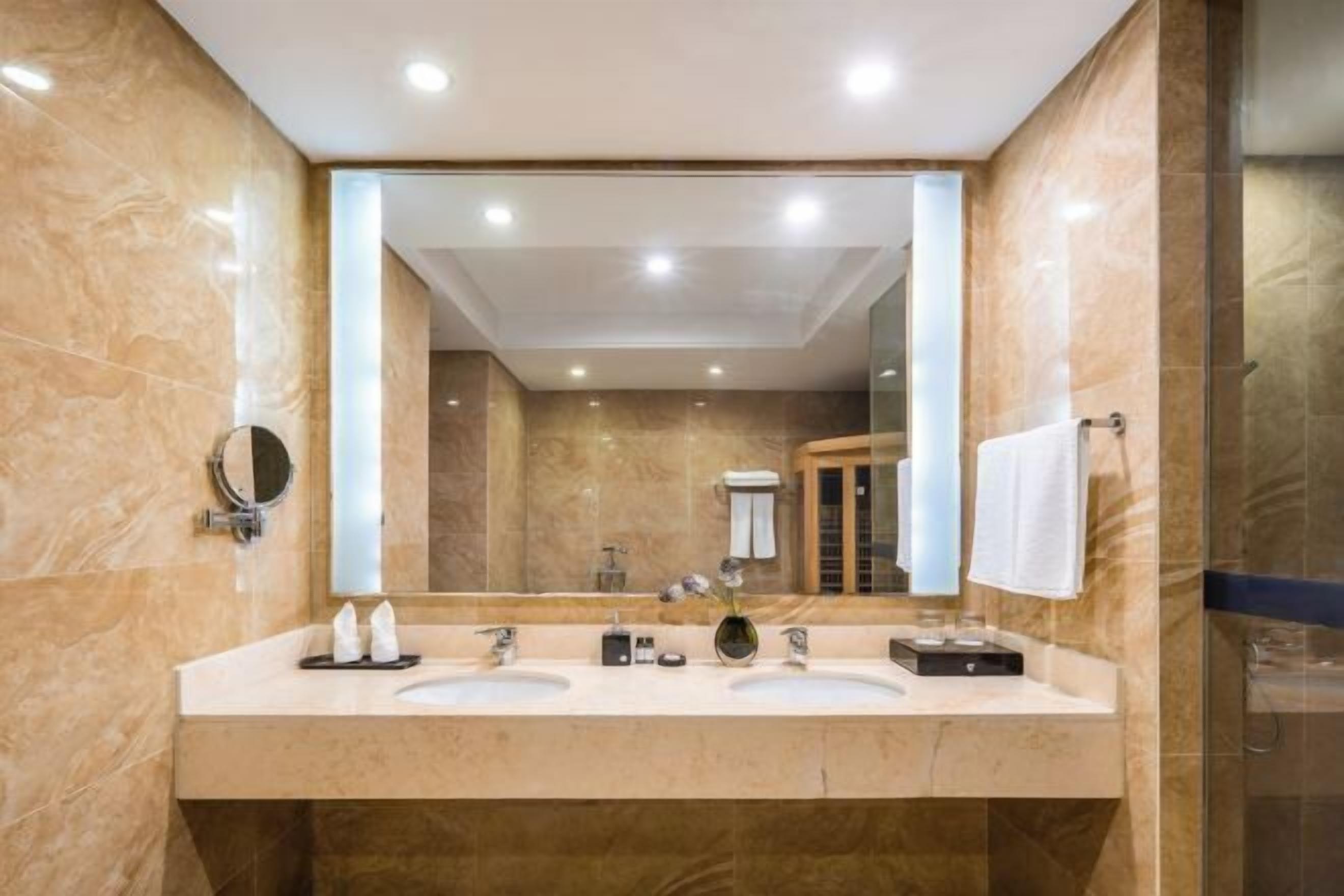 Un baño moderno con dos lavamanos, un espejo grande y un box de ducha de vidrio.