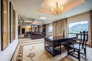 A spacious room with a large desk, chairs, a chandelier, and a view of a mountainous landscape. - Nanyue Resort (Huoshan)