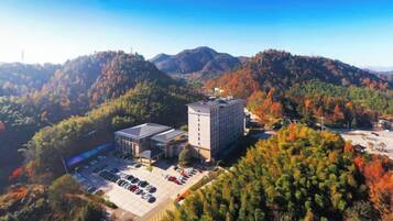 A building surrounded by a parking lot and dense forested hills.