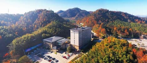 A building surrounded by a parking lot and dense forested hills.