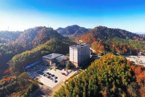 A building surrounded by a parking lot and dense forested hills. - Nanyue Resort (Huoshan)