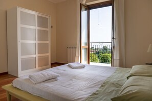 Une chambre à coucher avec un lit, une armoire, un radiateur et un balcon avec vue.