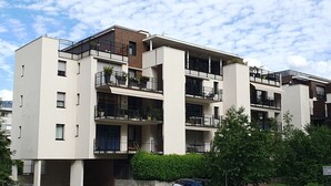 A multi-story residential building with balconies, a parking area, and a green landscape. - Aix-les-Bains Grand Port T2 Furnished 3 Stars Terrace 57m2 (Aix-les-Bains)