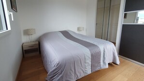 A bedroom with a bed, a nightstand, a lamp, and a wardrobe. - Aix-les-Bains Grand Port T2 Furnished 3 Stars Terrace 57m2 (Aix-les-Bains)