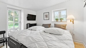 A bedroom with a bed, a TV, a window with plants, and a lamp. - Stunning home in Nørre Nebel (Nørre Nebel)