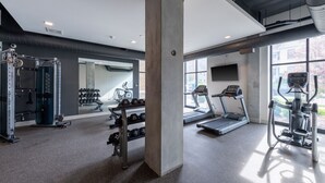 Ein modernes Fitnessstudio mit Laufbändern, Krafttrainingsgeräten und Kurzhanteln.