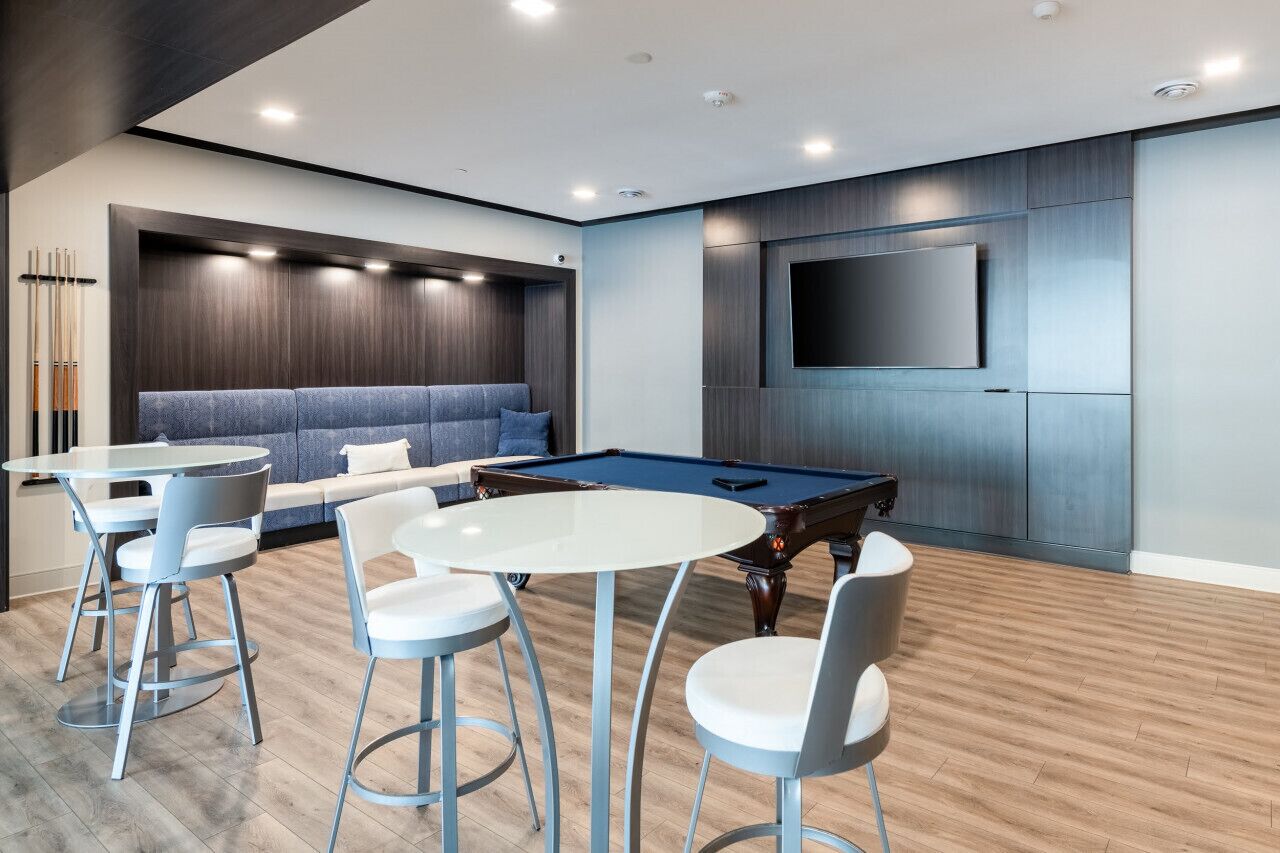 Una sala de estar moderna con una mesa de billar, un sofá y un televisor montado en la pared.
