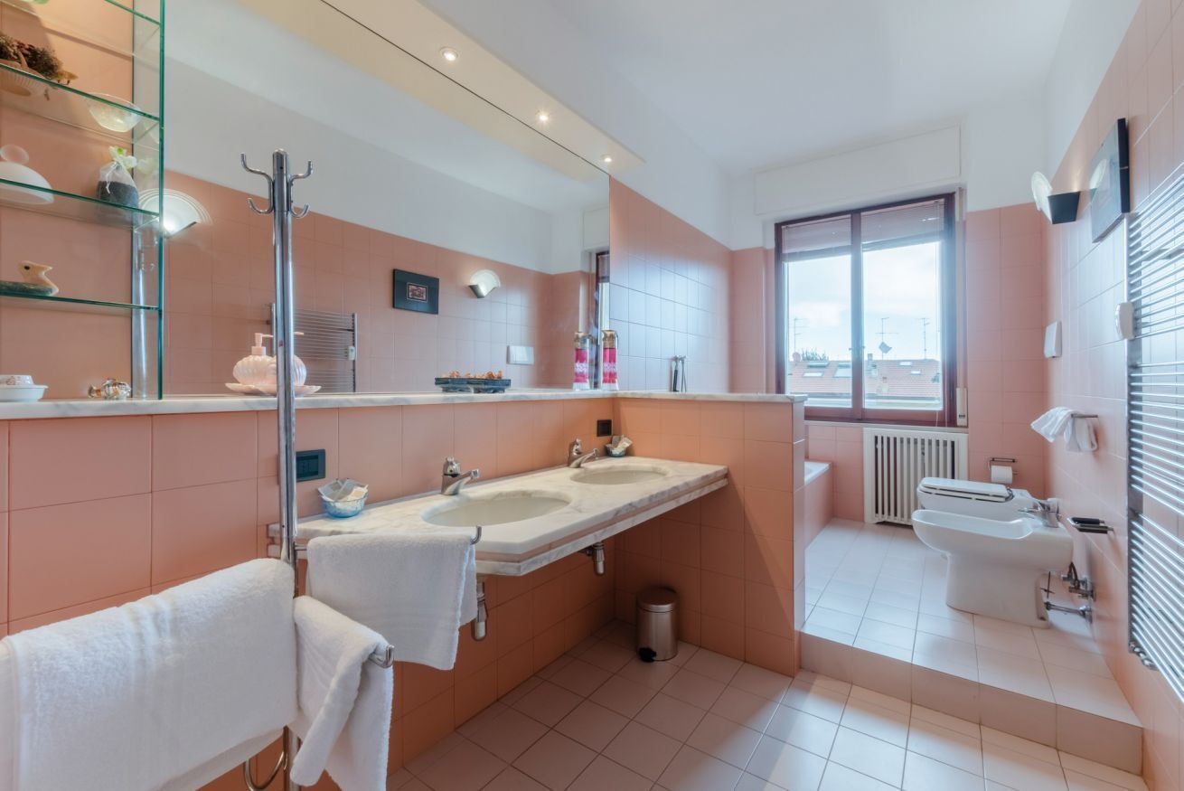 A modern bathroom with two sinks, a large mirror, and a toilet.