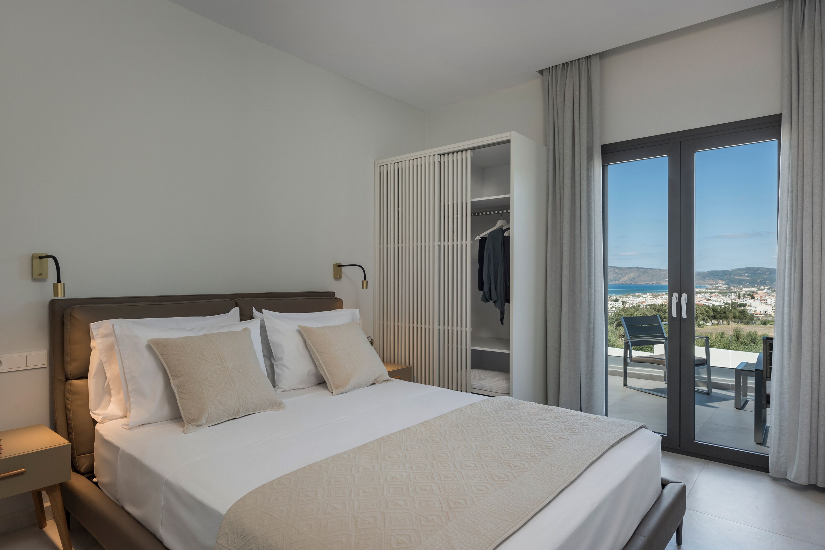 Habitació d'hotel moderna amb un llit gran, un armari encastat i un balcó amb vistes.