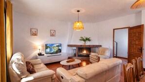 A living room with a sofa, armchairs, a TV, a fireplace, and a dining area with chairs. - Torcal 1 - Magnificent Villa for 8 People, Heated Pool, A/C, WIFI, Pet friendly! (Comares)
