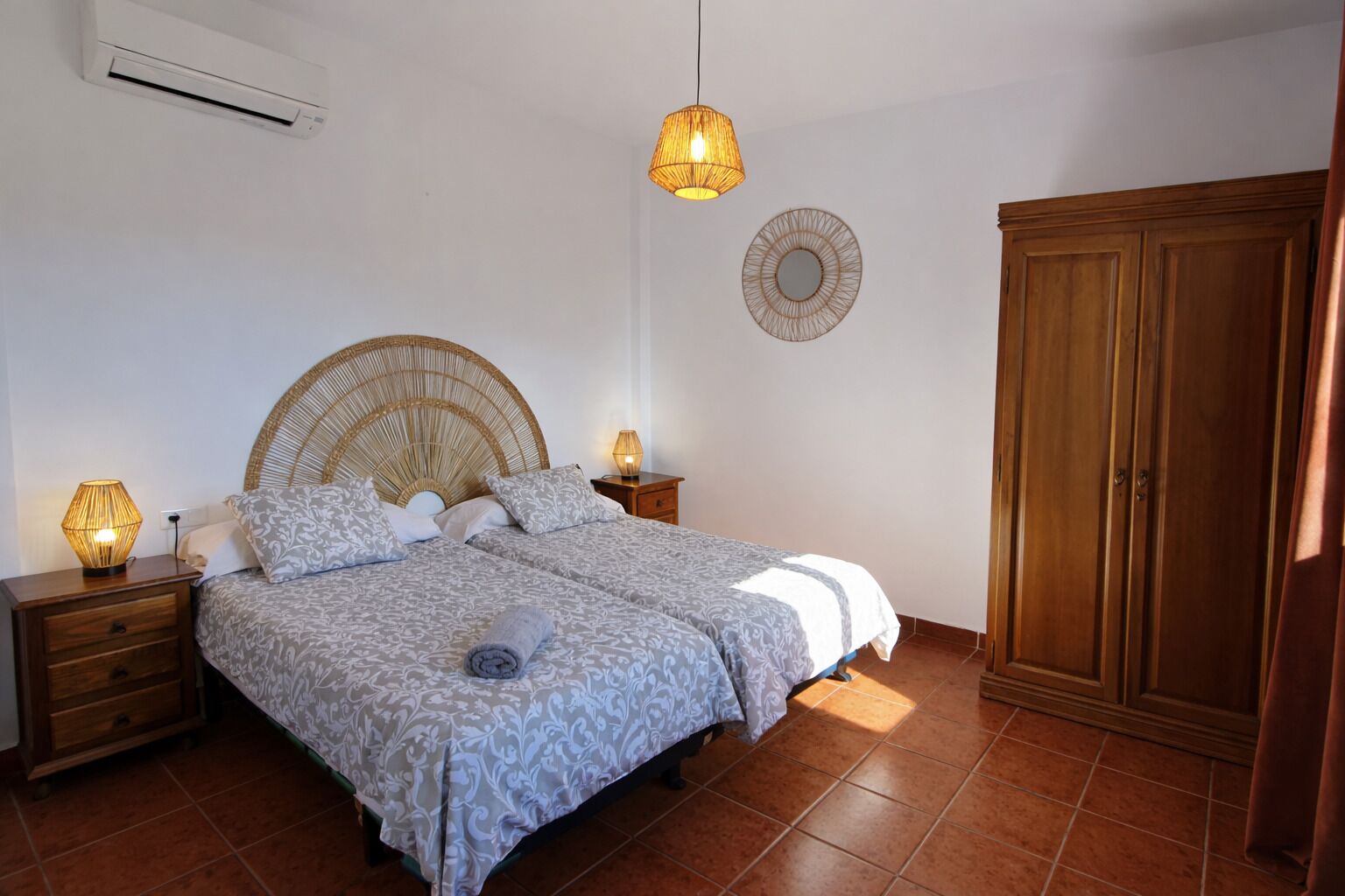 A bedroom with a bed, bedside tables, a wardrobe, and a wall-mounted air conditioner.