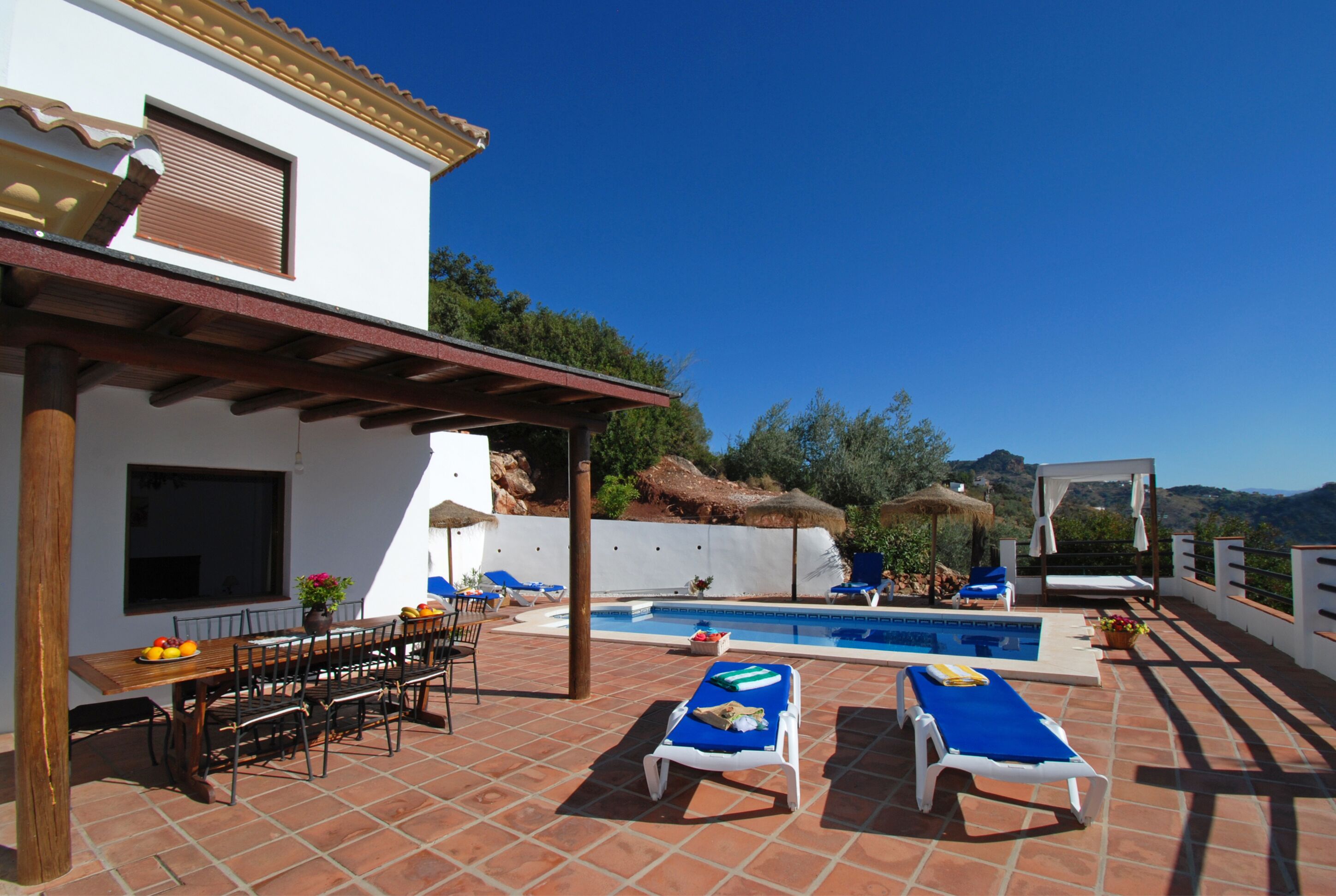 A rooftop pool area with lounge chairs and a dining table.