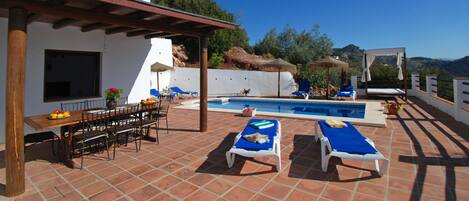 A rooftop pool area with lounge chairs and a dining table.
