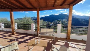 A covered outdoor seating area with a view of mountains and a town. - Torcal 1 - Magnificent Villa for 8 People, Heated Pool, A/C, WIFI, Pet friendly! (Comares)