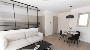 Een moderne woonkamer met een bank, een salontafel en een eethoek met stoelen en een tafel.
