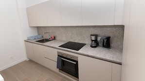 Een moderne keuken met een ingebouwde kookplaat, oven en spoelbak, plus een koffiezetapparaat en waterkoker.
