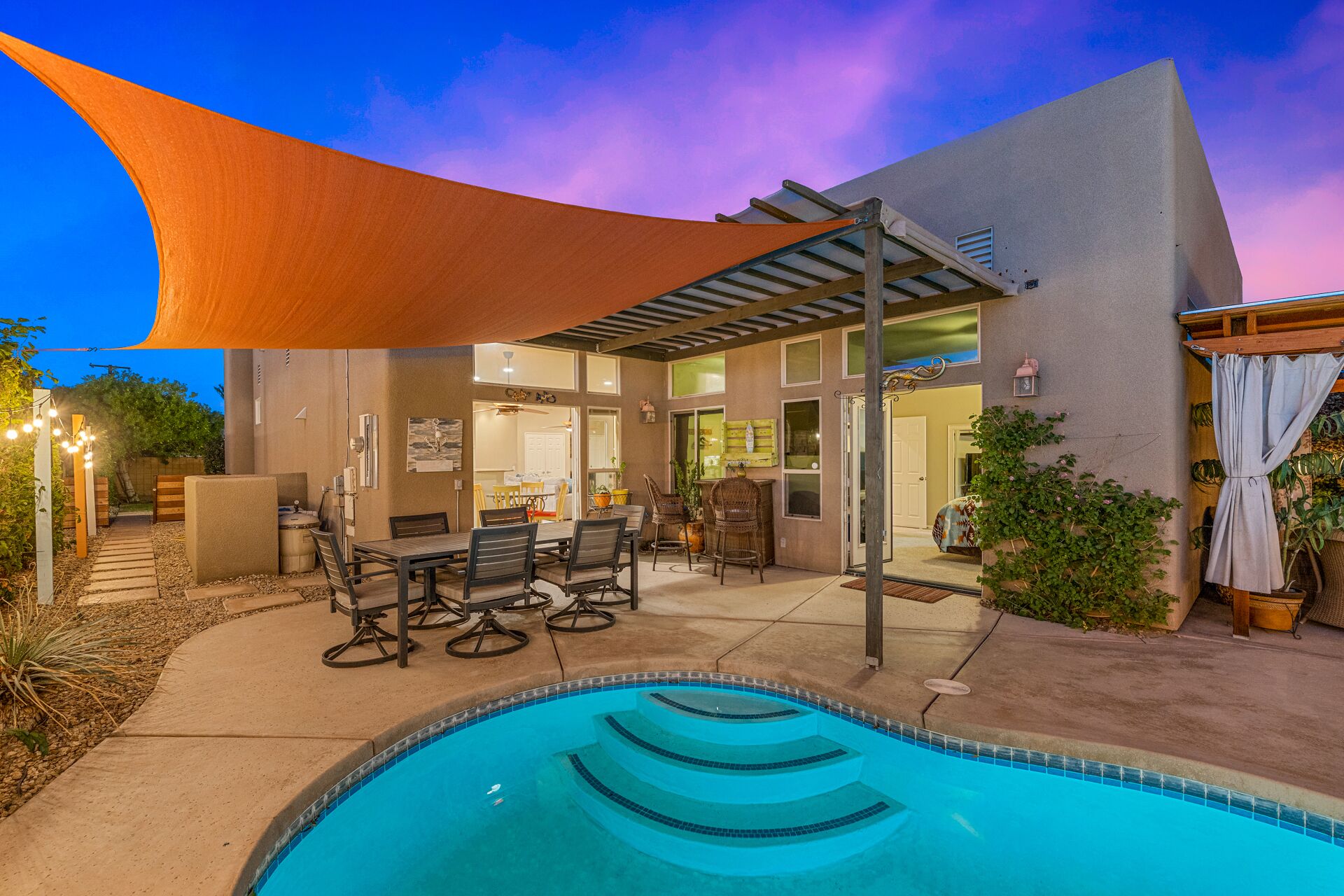 A poolside area with a covered patio, outdoor seating, and a view of the pool.