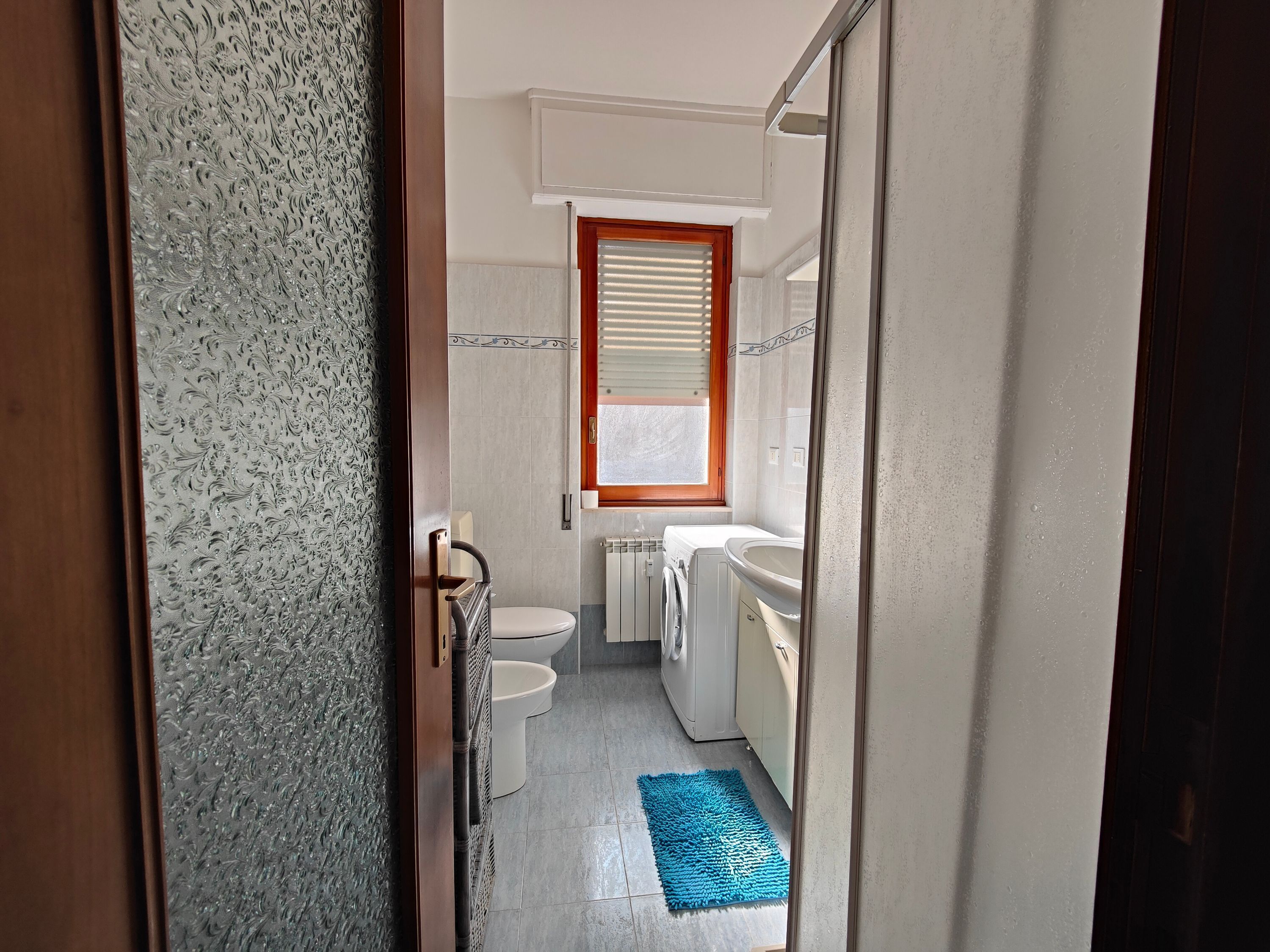 A compact bathroom with a toilet, washing machine, and sink.