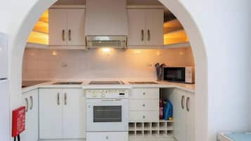 A compact kitchen with white cabinets, a built-in oven, a microwave, and a small sink.