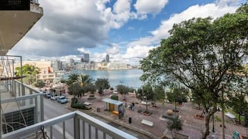 A balcony with a view of a cityscape, including buildings and a body of water.