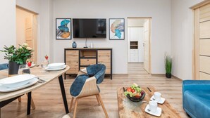 En moderne stue med spiseplads, et fladskærms-tv og kunst på væggen.