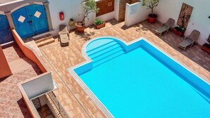 A swimming pool with a sun terrace, potted plants, and a blue door. - Studio for 3 people with air conditioning (Santa Teresa di Gallura)