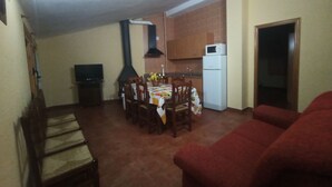 Un ambiente compatto con angolo ristoro, cucina, divano e televisione.