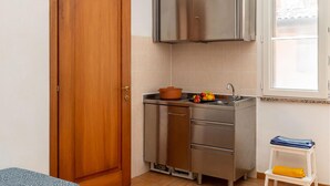 Une cuisine de taille réduite, dotée d’une porte en bois, de placards en acier inoxydable, d’un évier et d’une petite fenêtre.