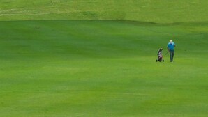 Une personne marchant sur un terrain de golf avec un sac de golf.