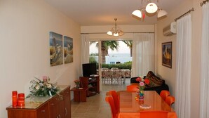 A dining area with a table and chairs, a television, and a view of the outdoors. - On the beach house latsi (Poli Crysochous)