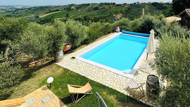 A rectangular swimming pool with a stone border, surrounded by a grassy area and a stone patio. - Villa seaview and private pool (Torrevecchia Teatina)