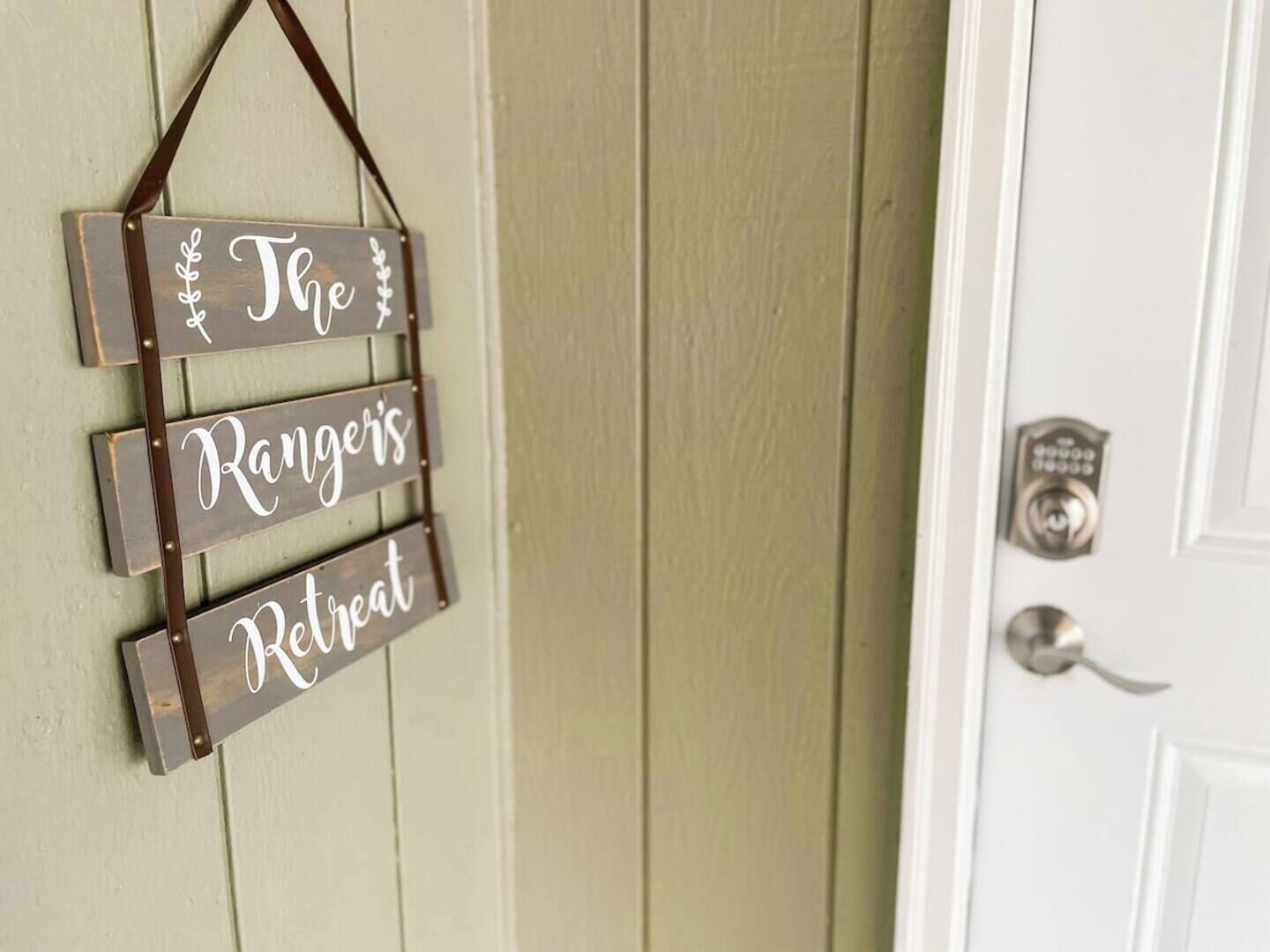 Un letrero de madera con el texto 'The Rangers Retreat' colgado de una puerta.
