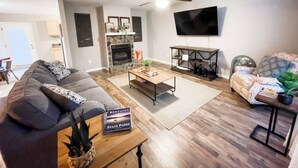 Un salon doté d’une cheminée, d’un téléviseur à écran plat fixé au mur et d’un ventilateur de plafond.