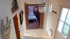 Ein Flur, der zu einem Schlafzimmer führt, mit einem Bett, einer Pendelleuchte und einem Fenster mit Blick.