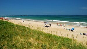 A beach with a pier extending into the water, clear skies, and people enjoying the beach. - Lotus House Pets Stay Free +Private Pool (Kill Devil Hills)