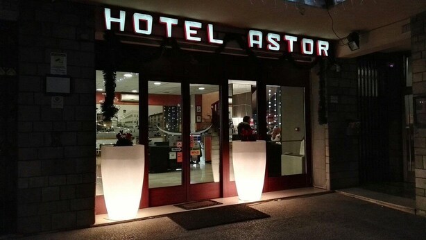 Exterior del Hotel Astor con señalización iluminada, amplios ventanales de vidrio y una entrada visible.