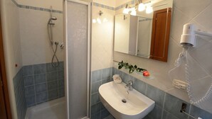 Un baño con ducha, lavabo y espejo.
