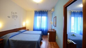 Un dormitorio con dos camas, un aparador de madera, un espejo y una pared con un dibujo floral.