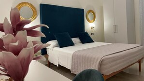 Un dormitori modern amb un llit gran, dues taules de nit, un armari i miralls decoratius a la paret.