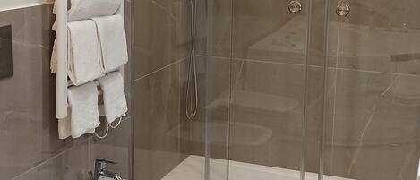 Un baño moderno con ducha acristalada, un bidé y un inodoro.