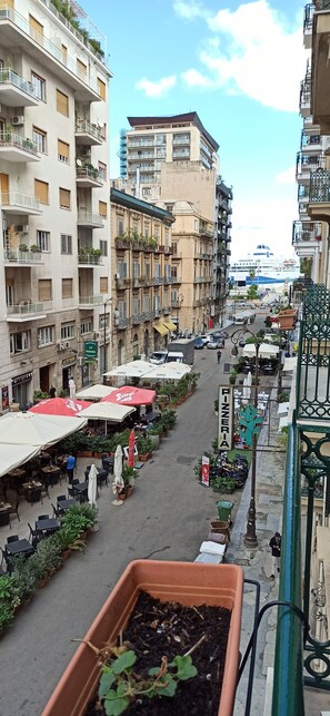 A street with outdoor seating, potted plants, and a sign for a pizzeria. - AMARIS (Palermo)