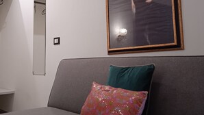 Un saló modern amb un sofà gris, un coixí decoratiu, un retrat emmarcat i un mirall a la paret.