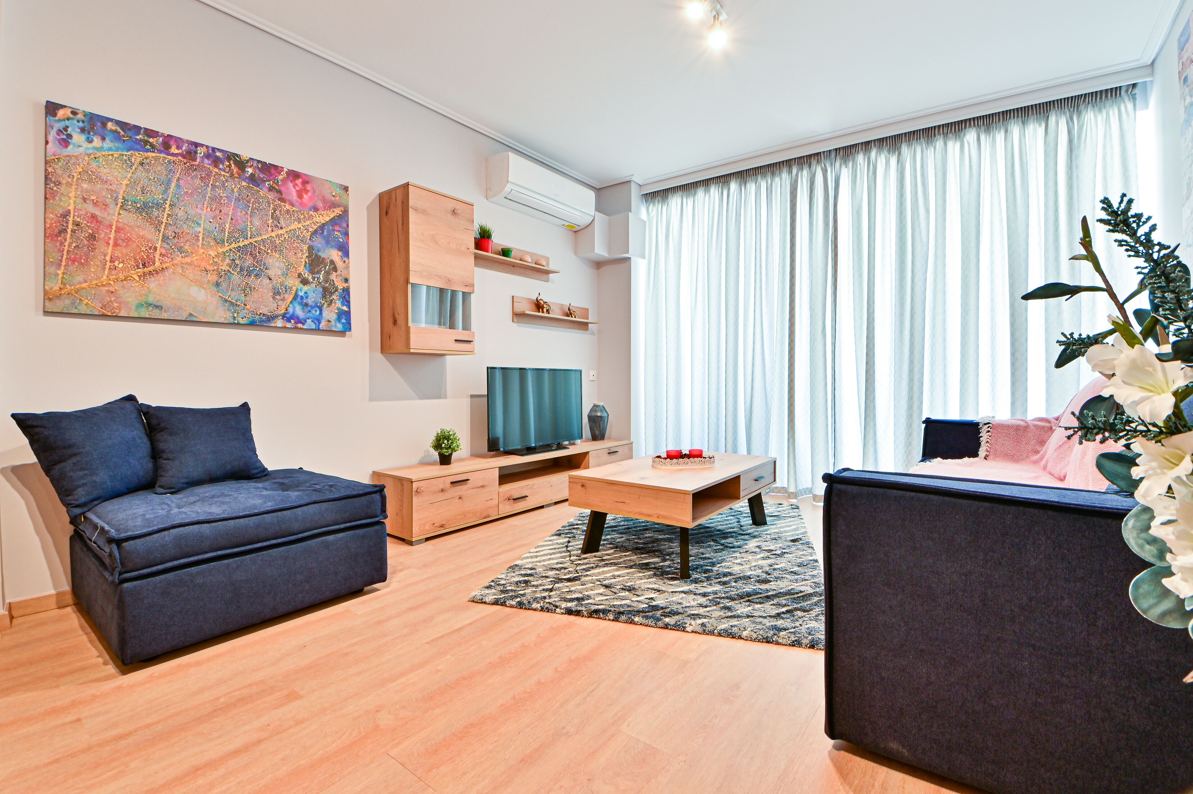 Un salon moderne comprenant un canapé, une table basse, un téléviseur et des objets décoratifs.