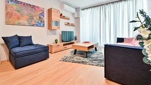 Una sala moderna con sofá, mesa de centro, televisor y elementos decorativos.