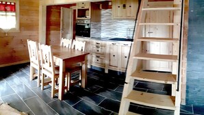 A wooden interior with a dining area, kitchen, and a wooden staircase. - CHALET L'ADRET (Bluffy)