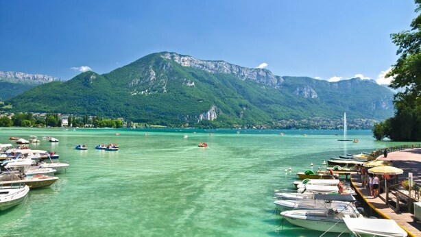 A marina with boats docked, a pier with people, and mountains in the background. - CHALET L'ADRET (Bluffy)