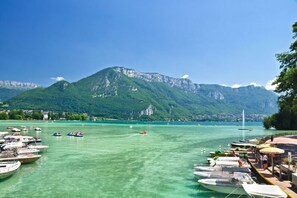Ein Yachthafen mit vertäuten Booten, eine Pier mit Menschen und Berge im Hintergrund.
