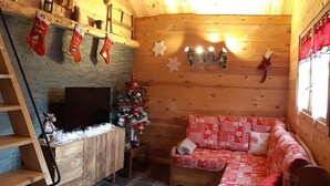 A cozy log cabin interior with a fireplace, a Christmas tree, a sofa, and a ladder. - CHALET L'ADRET (Bluffy)