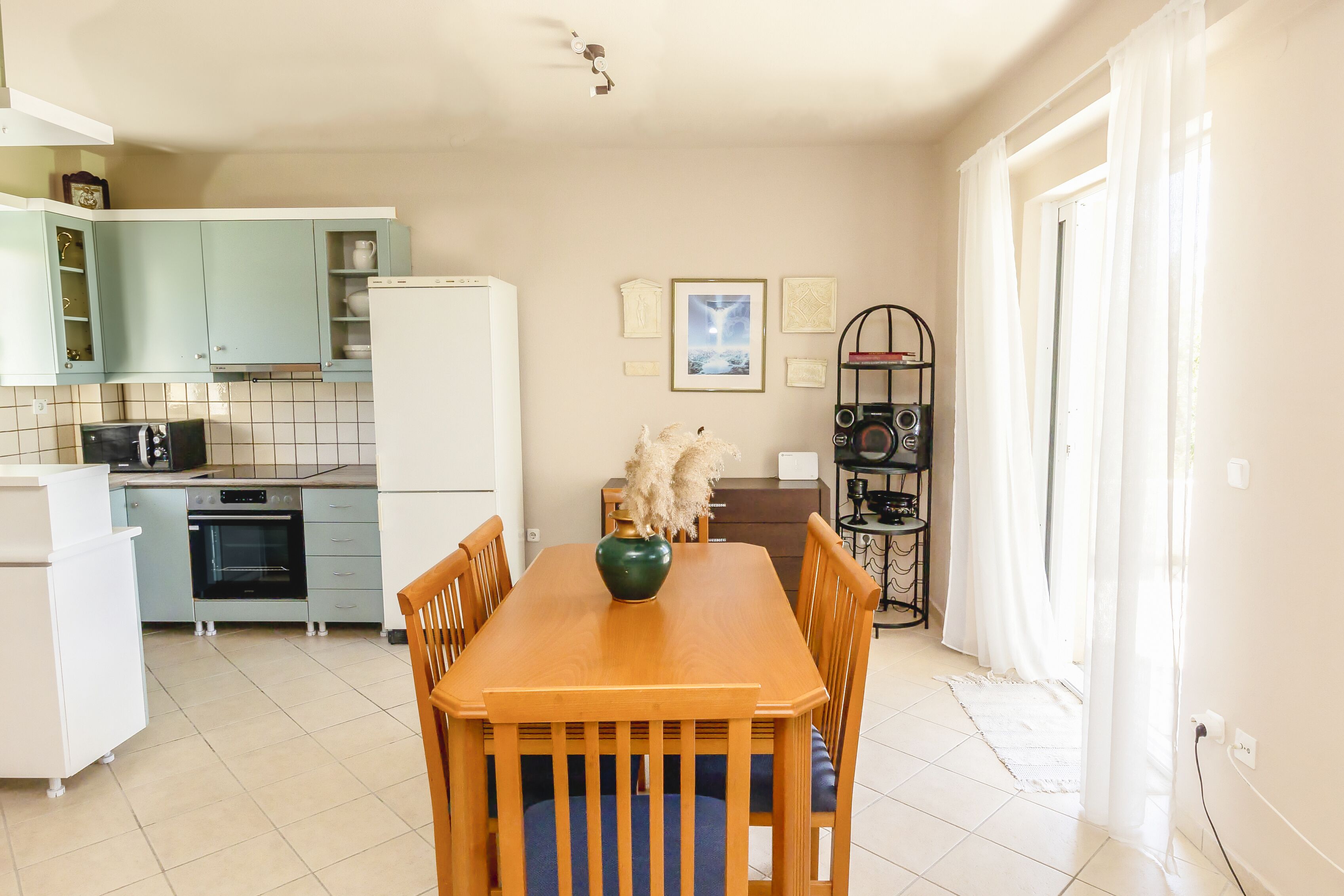 A compact kitchen with a dining table, chairs, a refrigerator, an oven, and a microwave.