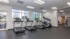 Een sportschool met loopbanden, een roeimachine en een gewichtbank.
